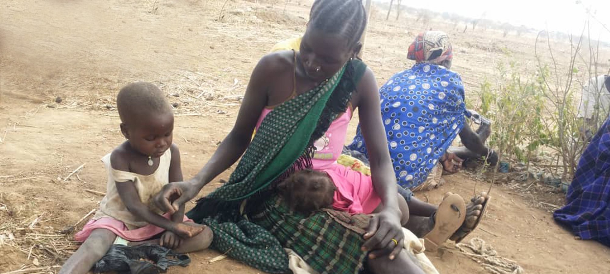 Women And Children Sitting On The Ground